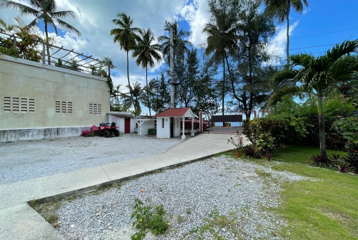 Entrada privada con palmeras y garita junto al mar
