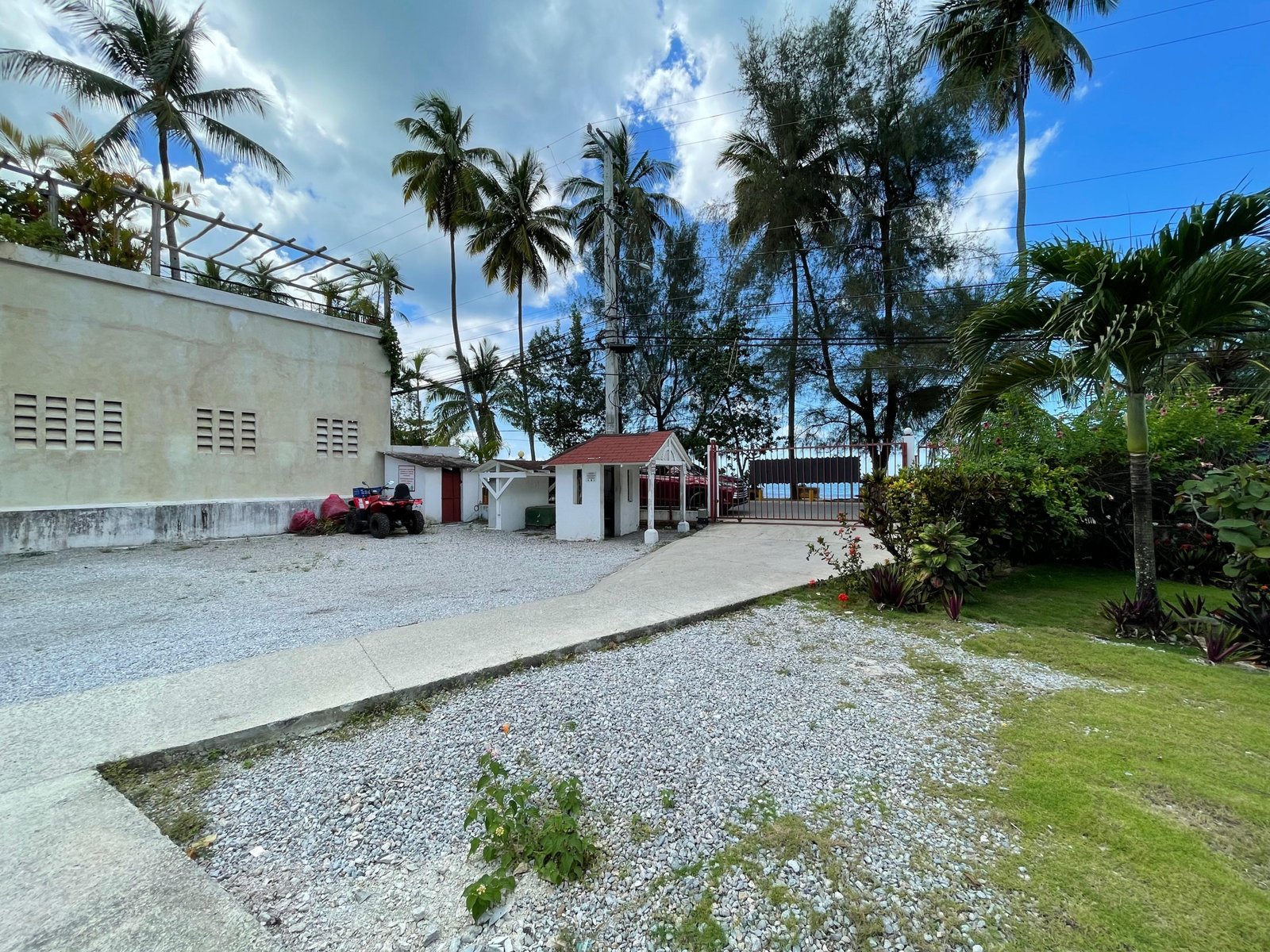 Entrada privada con palmeras y garita junto al mar