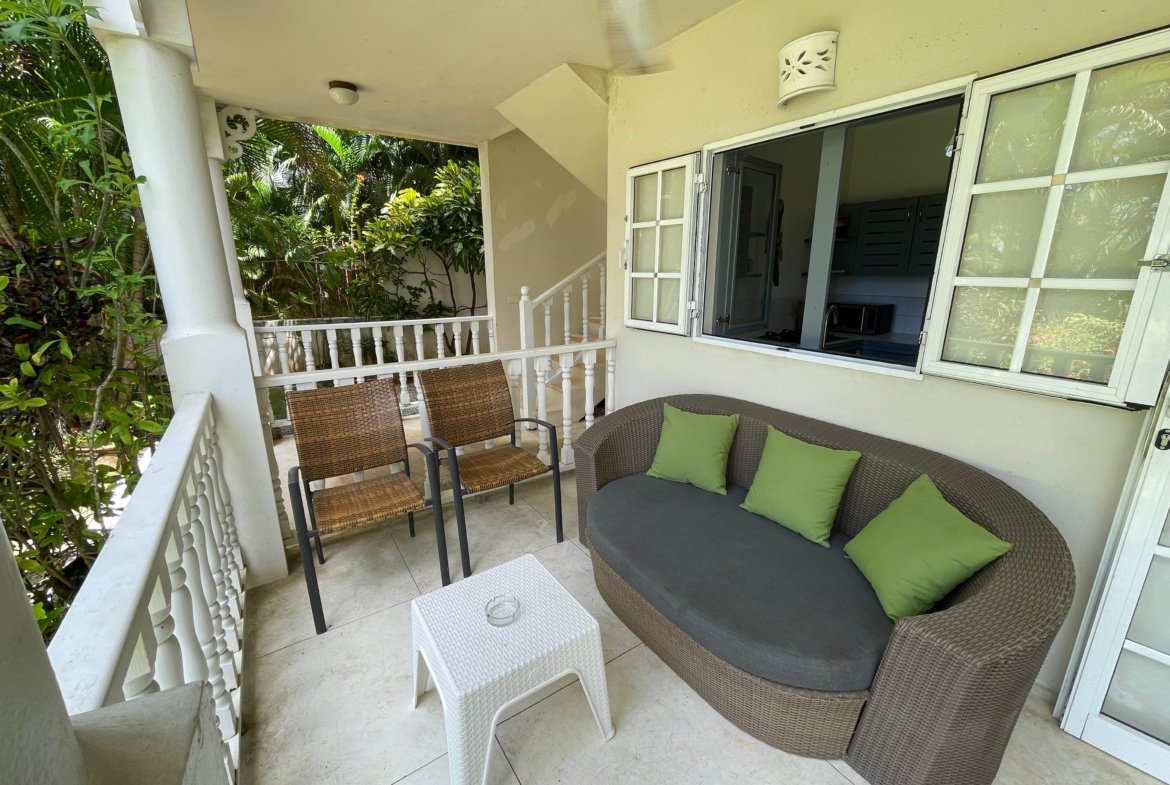 Terraza con sofá de mimbre y plantas tropicales