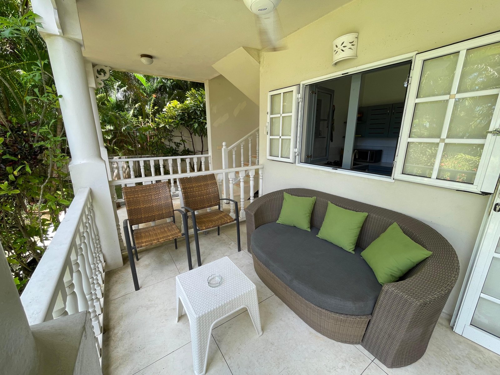 Terraza con sofá de mimbre y plantas tropicales