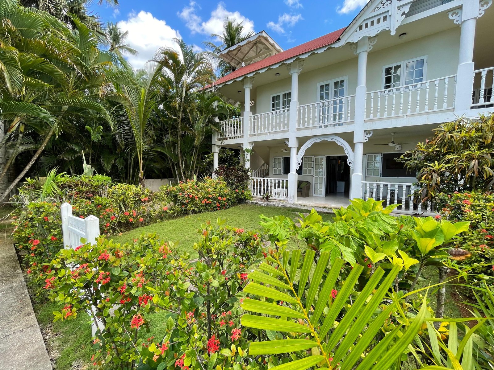 Maison tropicale avec jardin luxuriant et balcon blanc