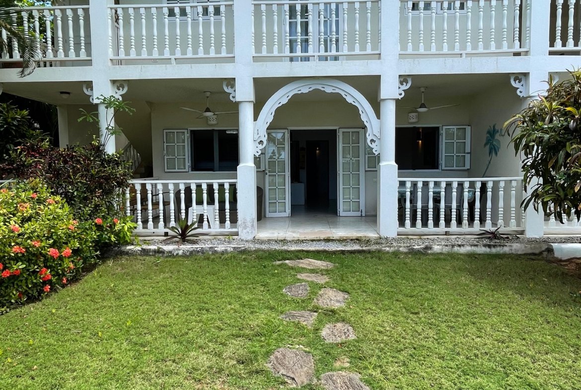 Casa colonial blanca con balcones y jardín tropical