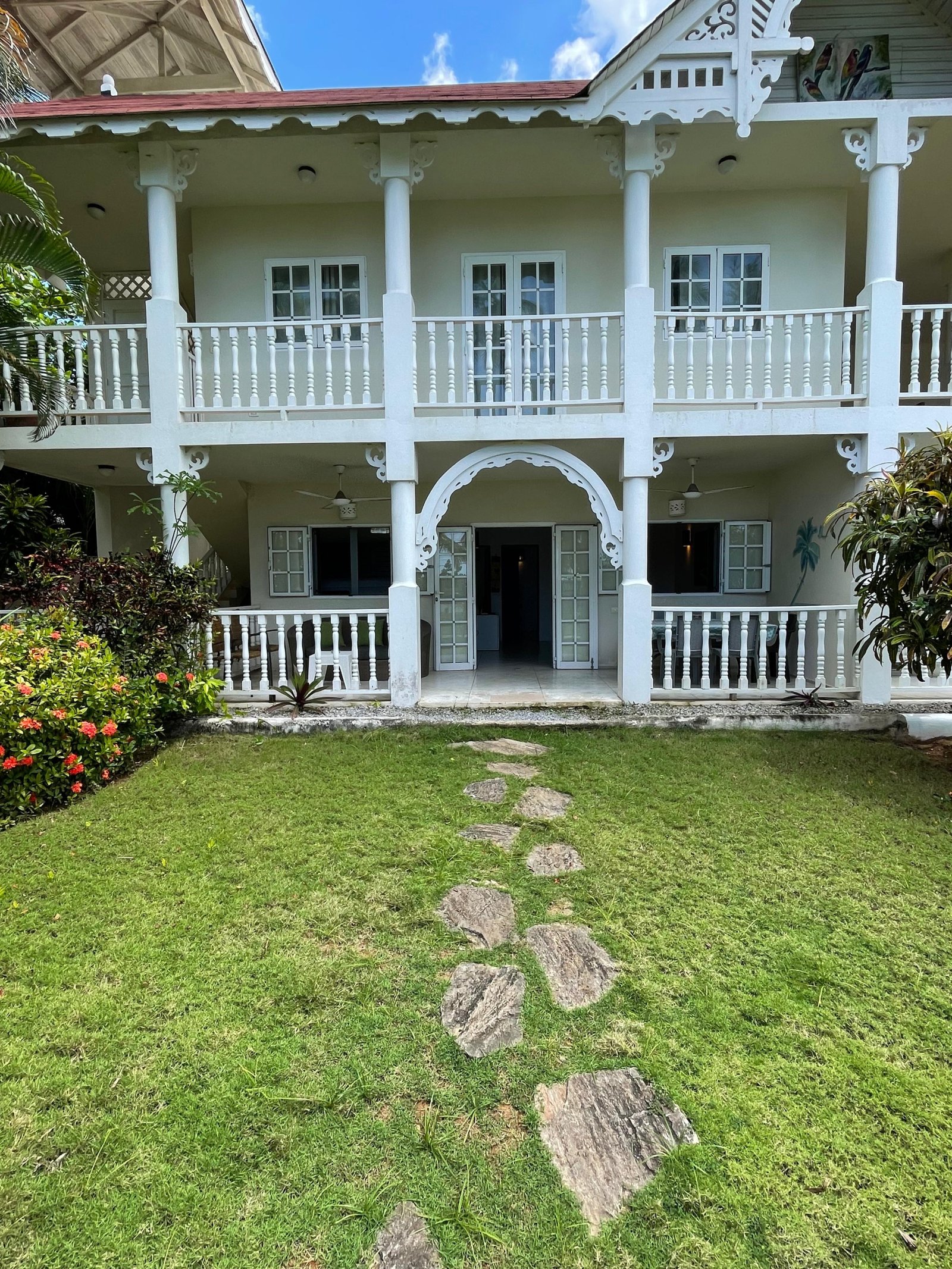 Casa colonial blanca con balcones y jardín tropical