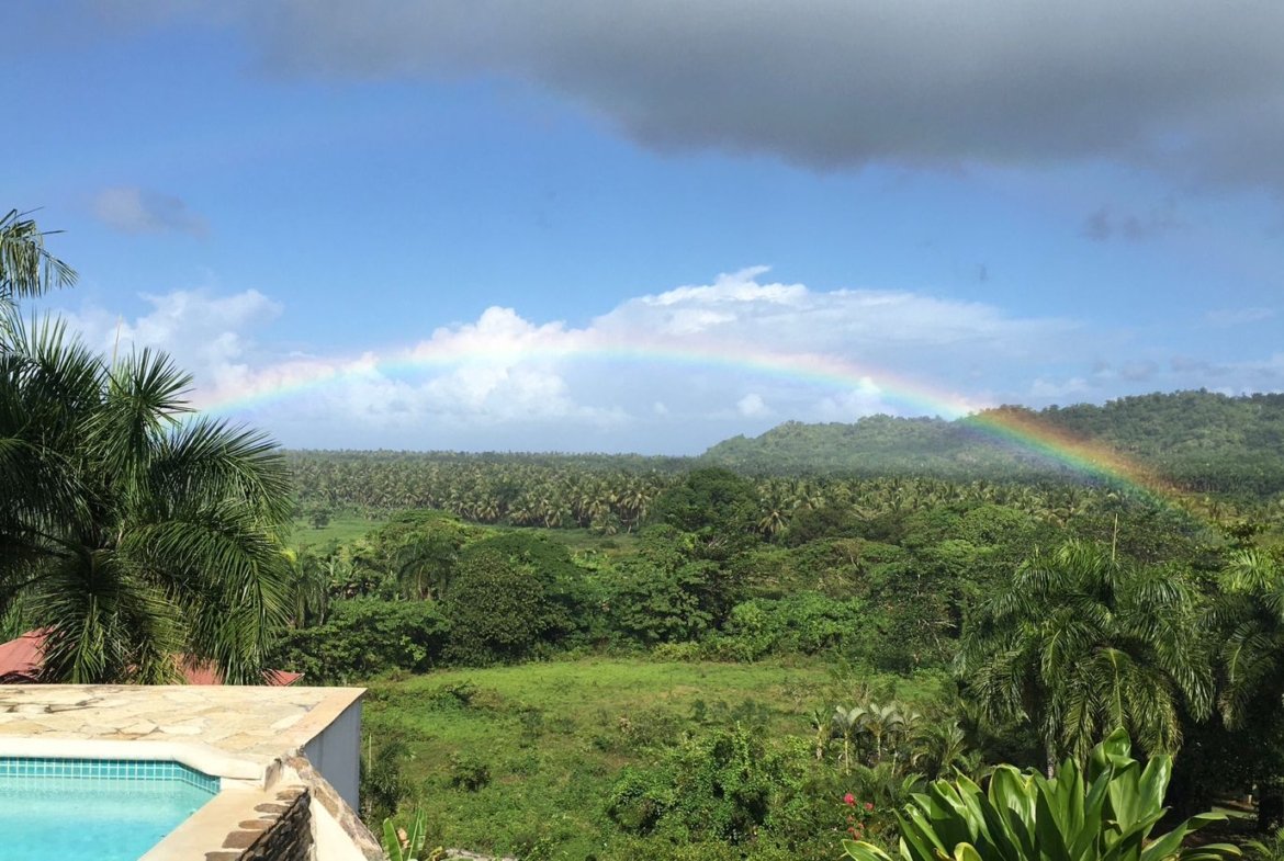 Arcoíris sobre paisaje tropical con piscina