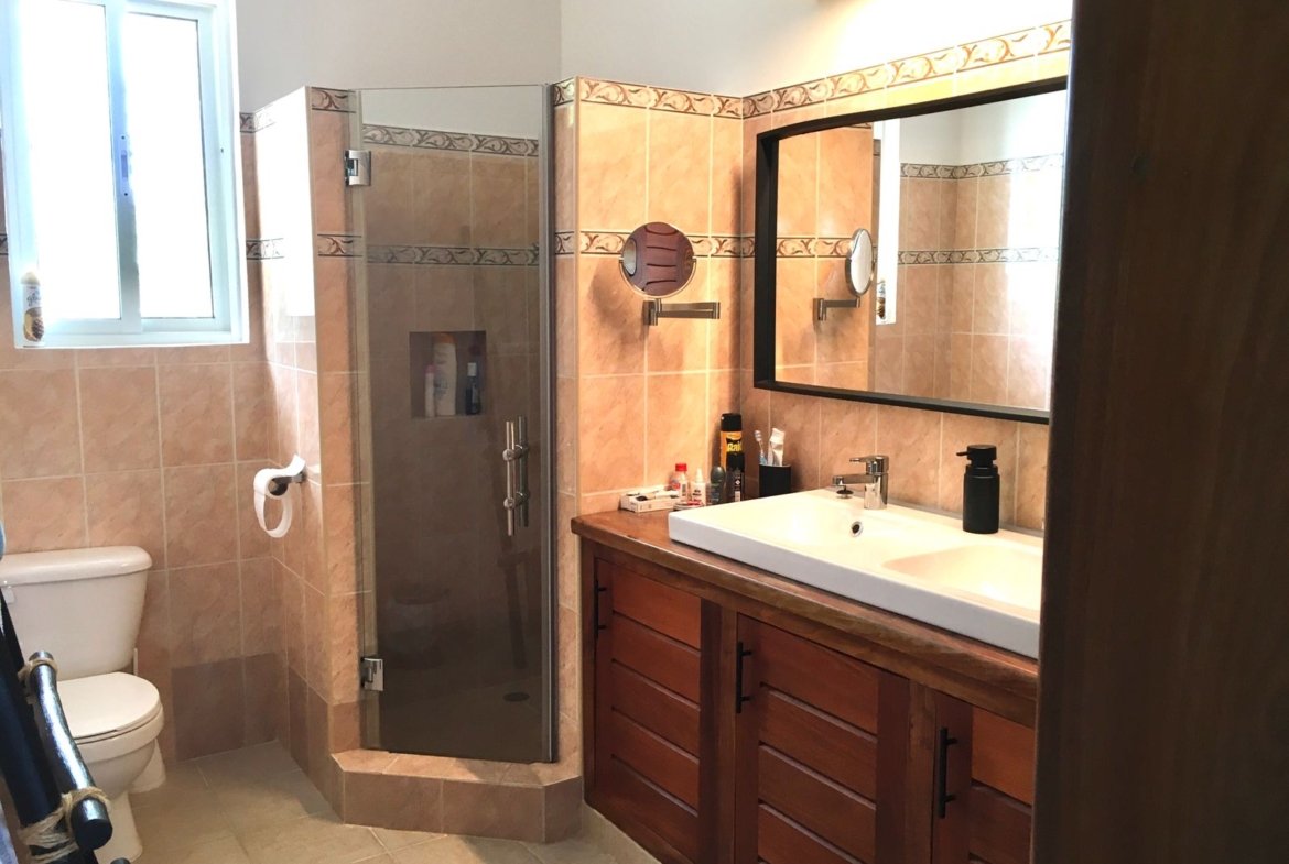 Baño moderno con ducha, lavabo y azulejos beige