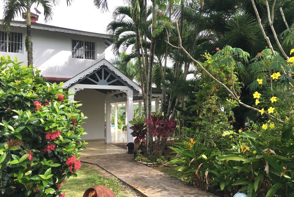Casa tropical rodeada de exuberante jardín y palmeras