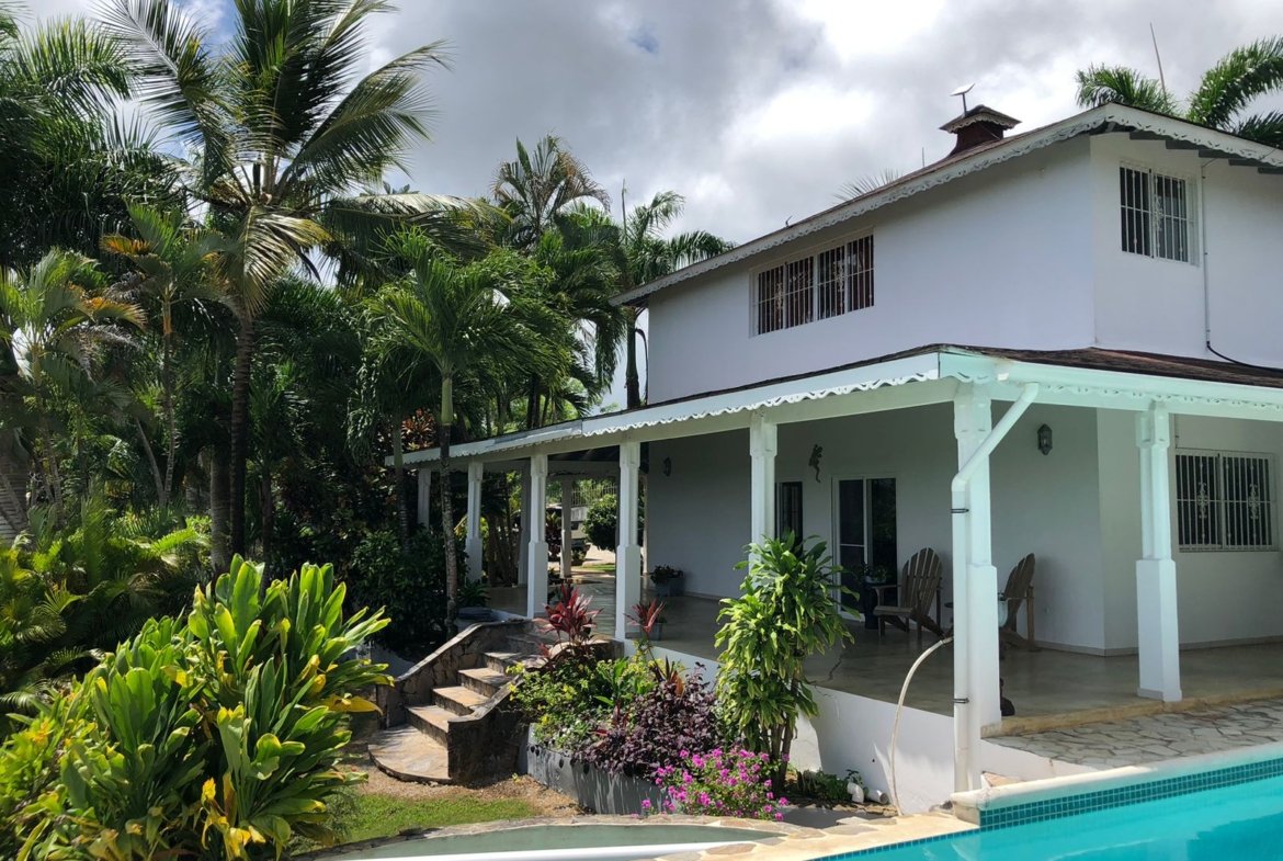 Casa tropical blanca con piscina y palmeras