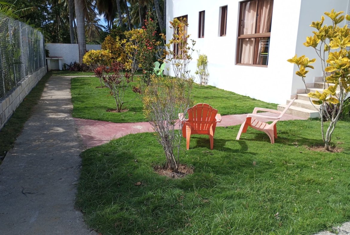 Jardín con sillas de plástico junto a casa blanca