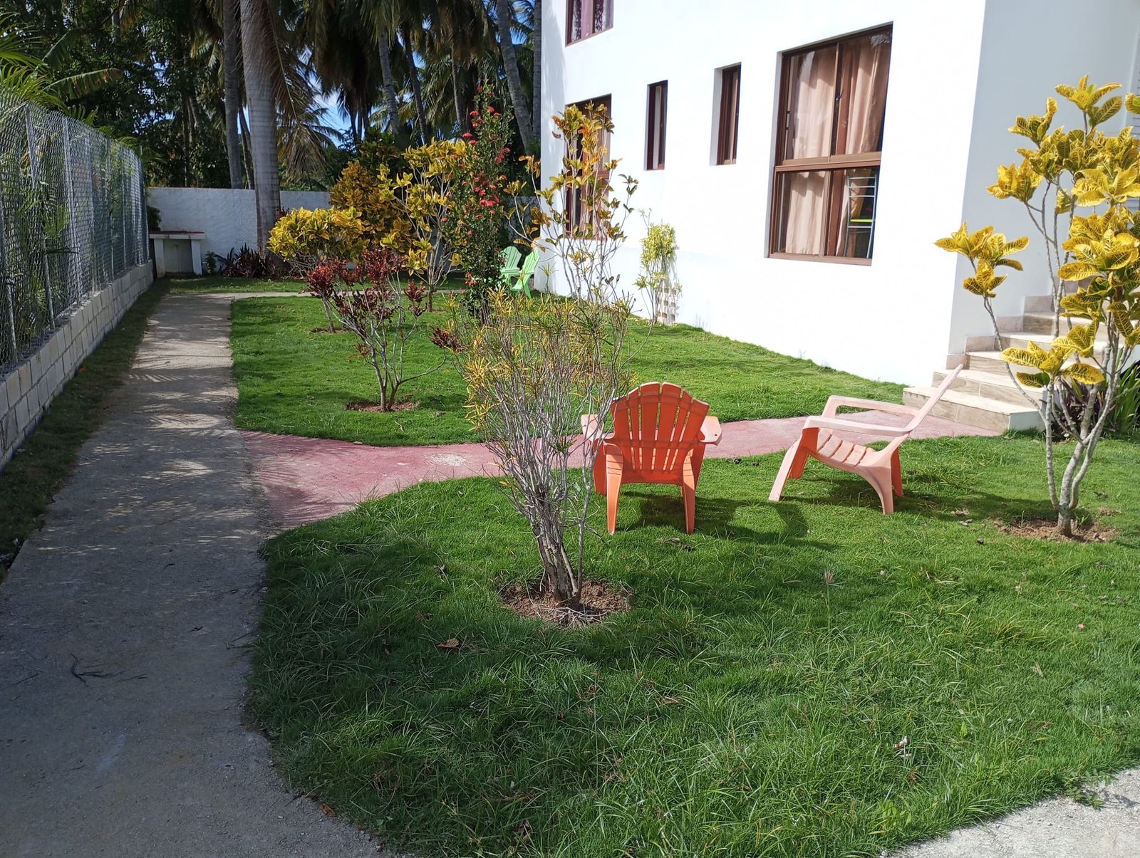 Apartamento en limon (2) Jardín con sillas de plástico junto a casa blanca