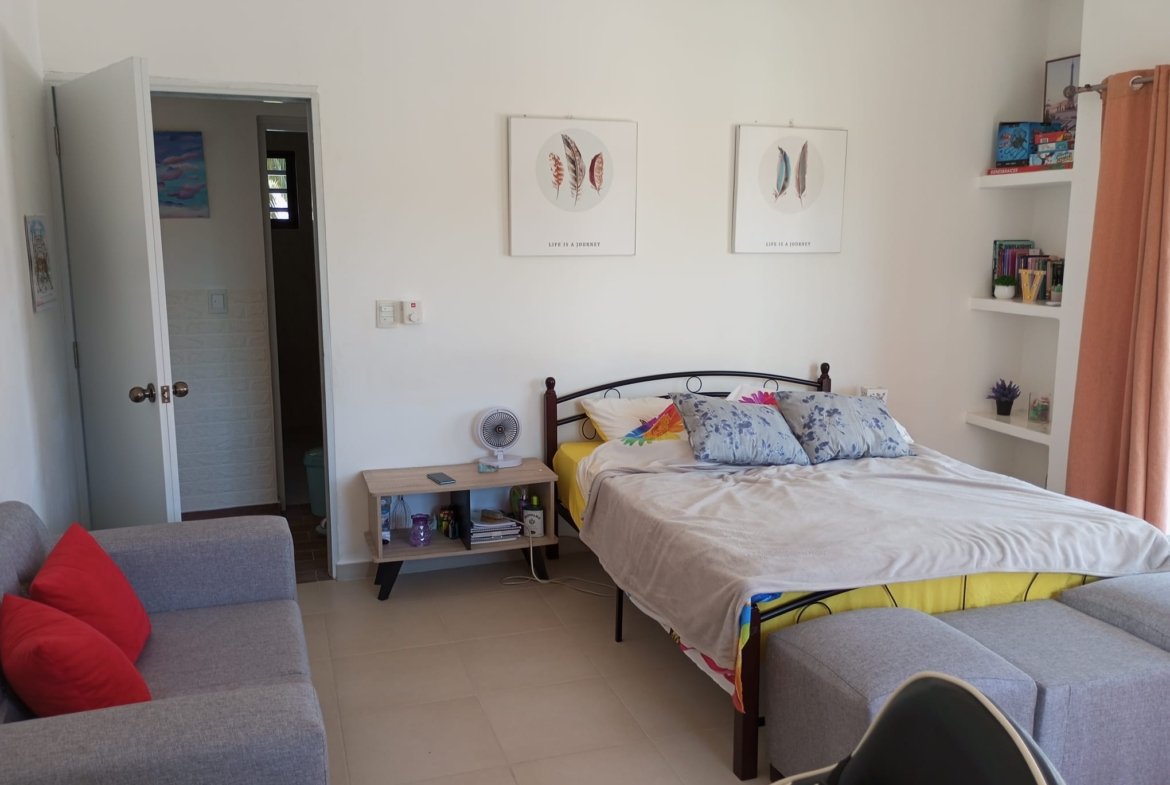 Dormitorio luminoso con cama doble y sofá gris