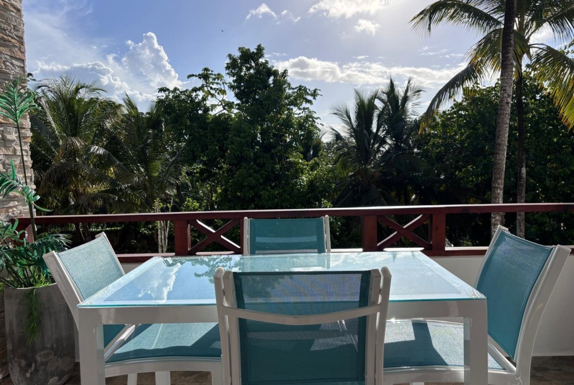 Terraza con mesa de cristal y palmeras tropicales