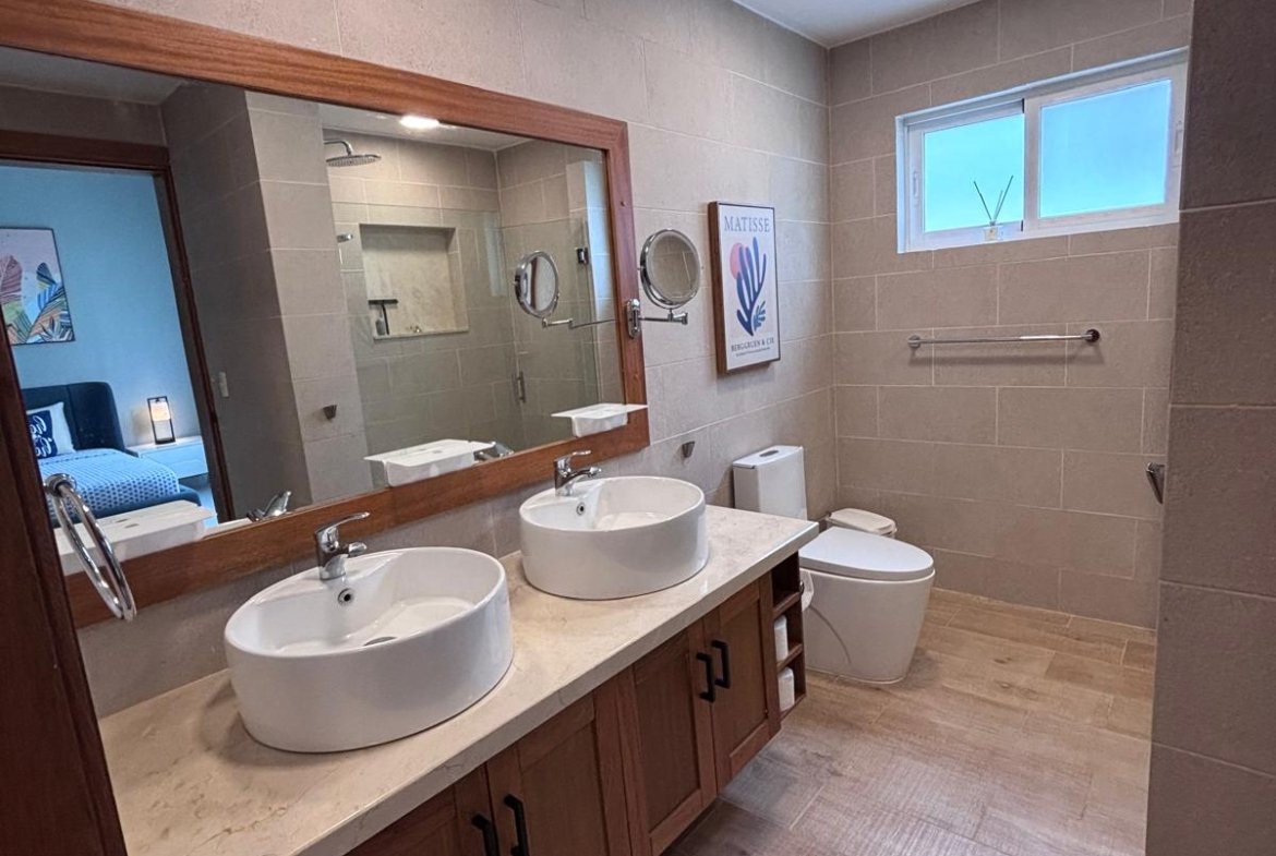 Baño moderno con doble lavabo y espejo grande