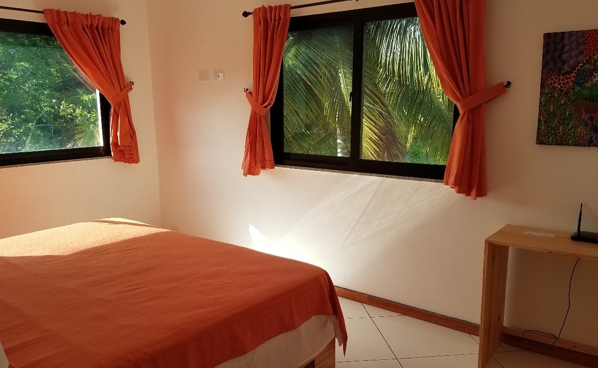 Dormitorio luminoso con colcha y cortinas naranjas