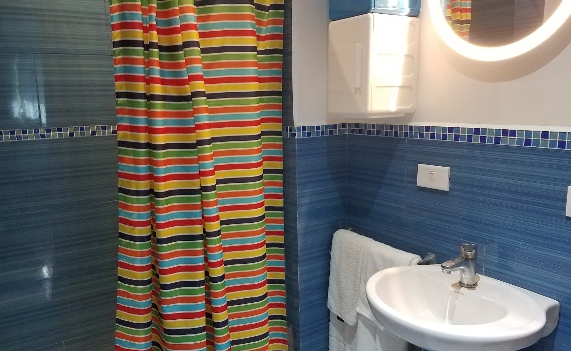 Baño con cortina colorida y azulejos azules