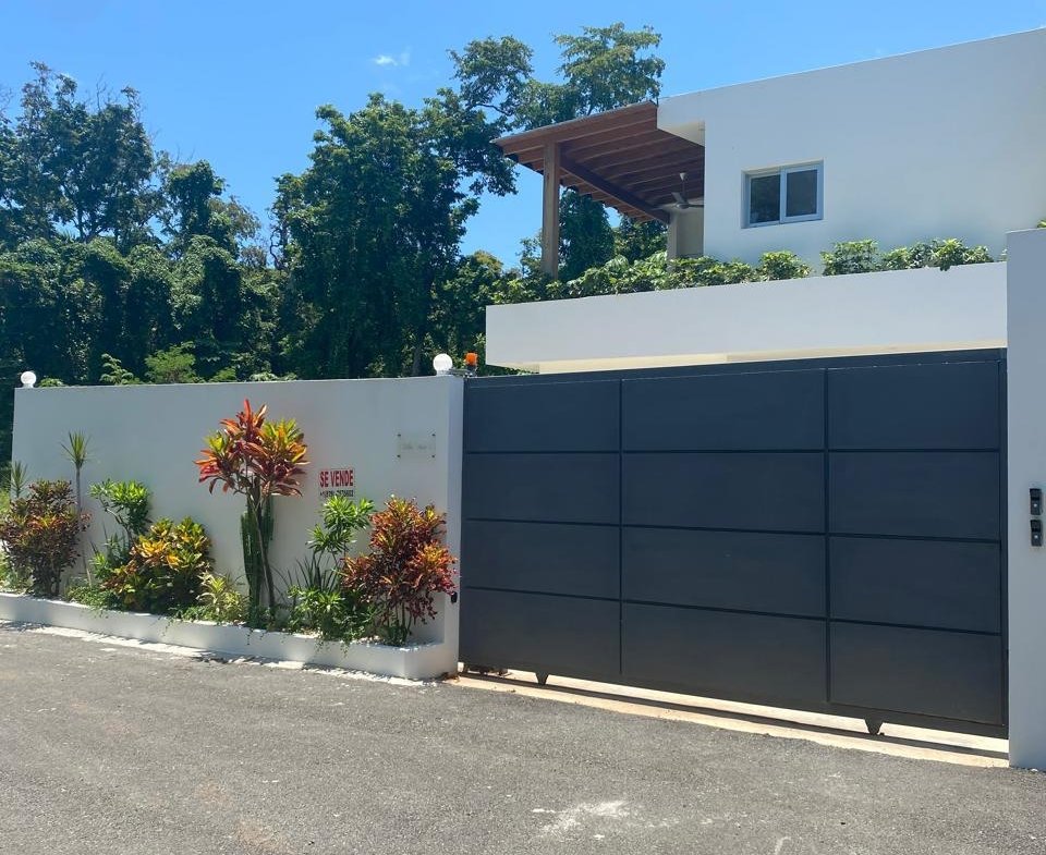 Casa moderna con puerta negra y jardín tropical