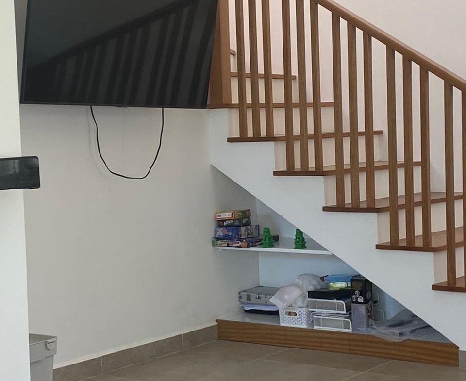 Televisor y escalera de madera en salón moderno