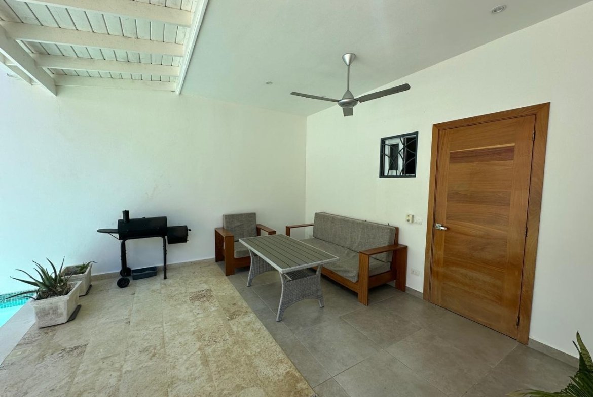 Terraza cubierta con sofá, mesa y barbacoa