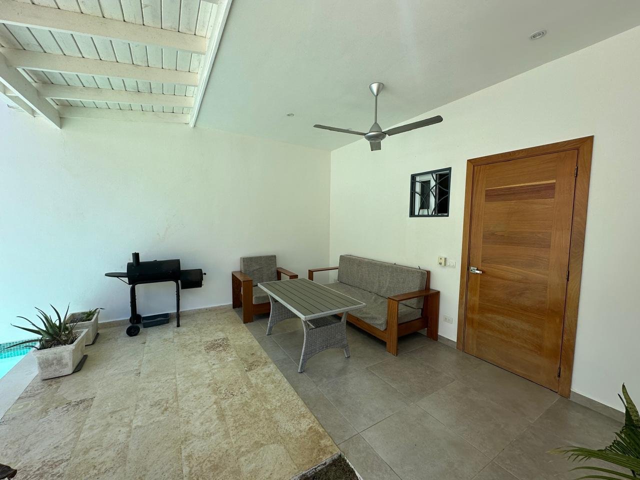 Terraza cubierta con sofá, mesa y barbacoa