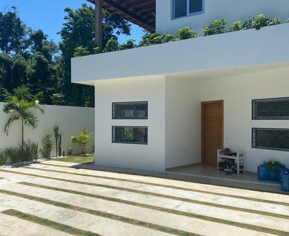 Casa moderna blanca con jardín y pérgola