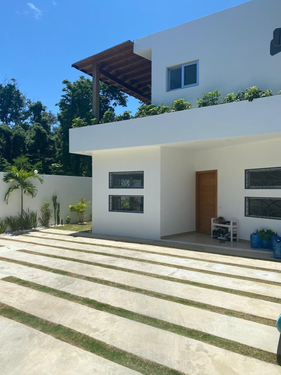 Casa moderna blanca con jardín y pérgola