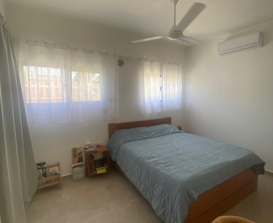 Dormitorio luminoso con cama doble y ventilador