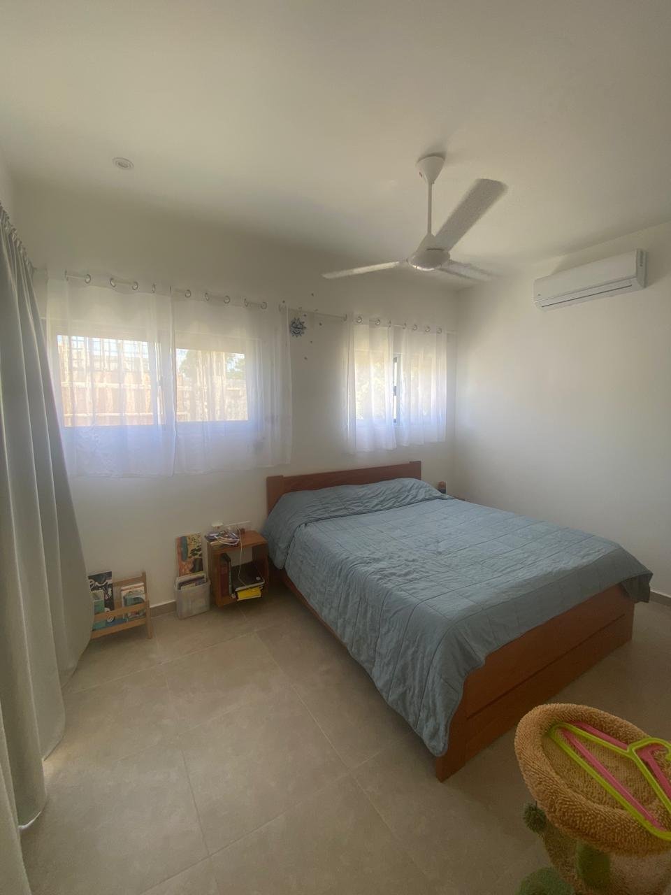Dormitorio luminoso con cama doble y ventilador
