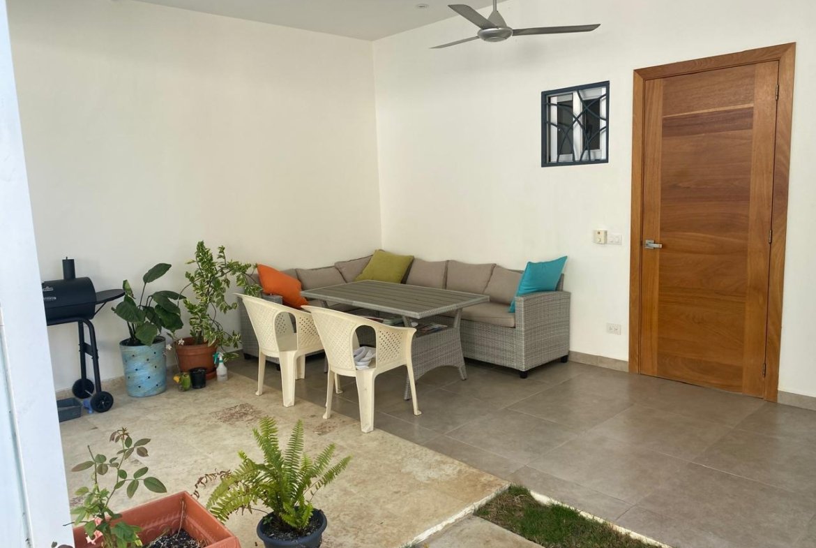 Porche cubierto con sofá, mesa y plantas