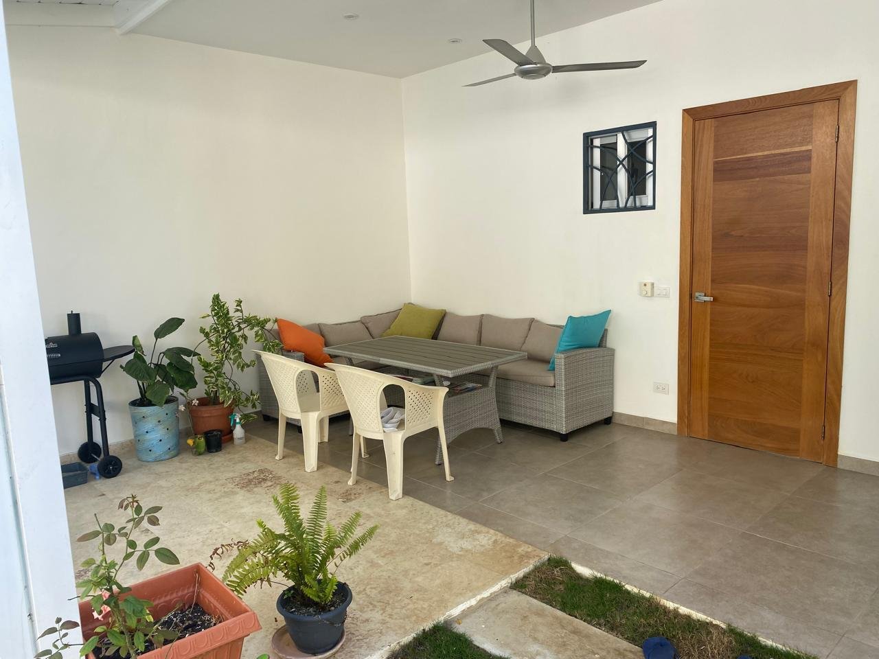 Porche cubierto con sofá, mesa y plantas