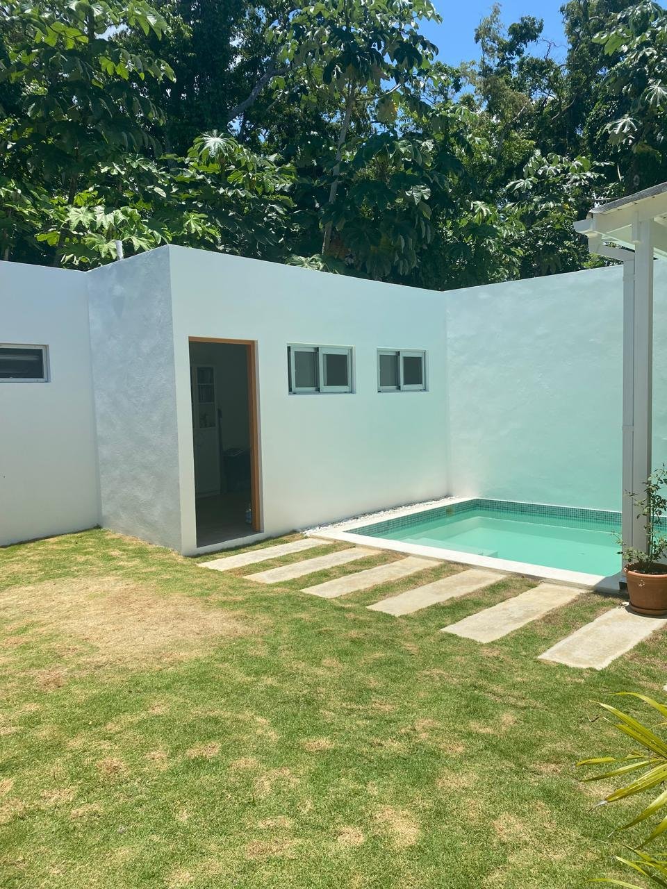 Casa moderna blanca con pequeña piscina y jardín