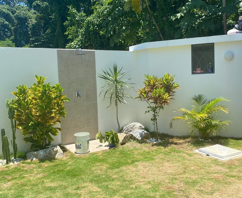 Ducha exterior en jardín tropical con césped