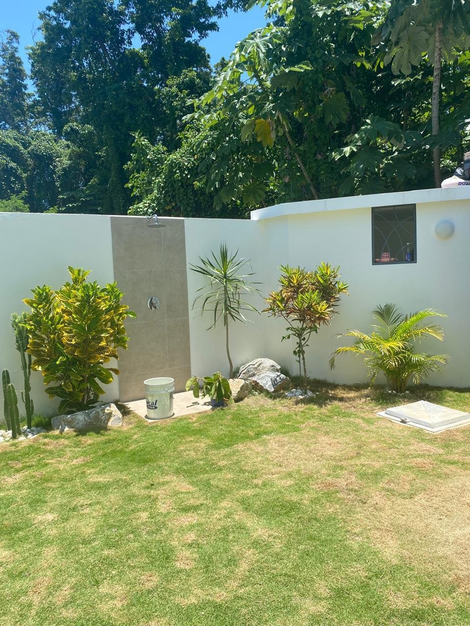 Ducha exterior en jardín tropical con césped
