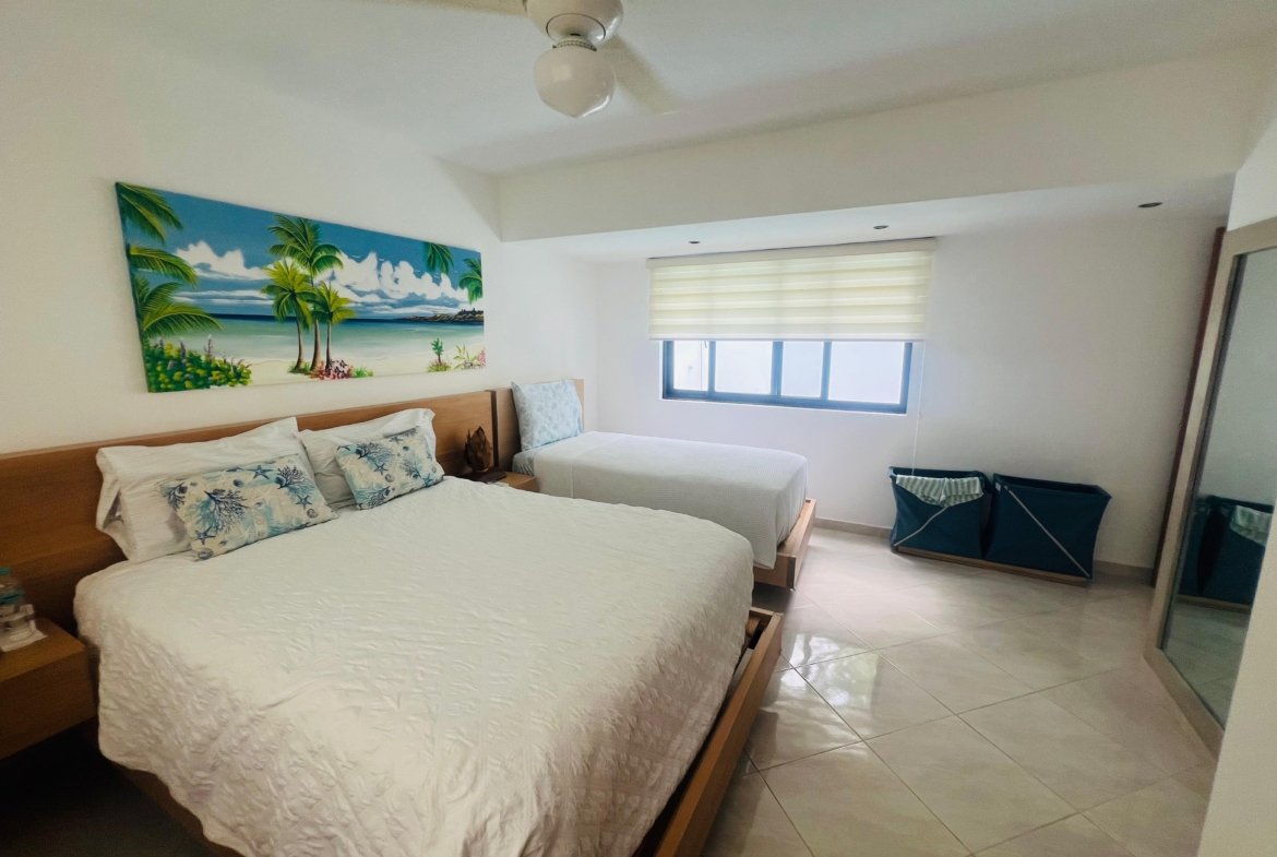 Dormitorio luminoso con cama doble y decoración tropical