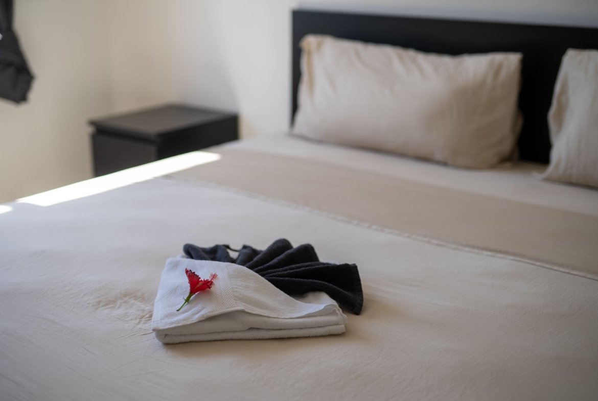 Cama ordenada con toallas y flor roja