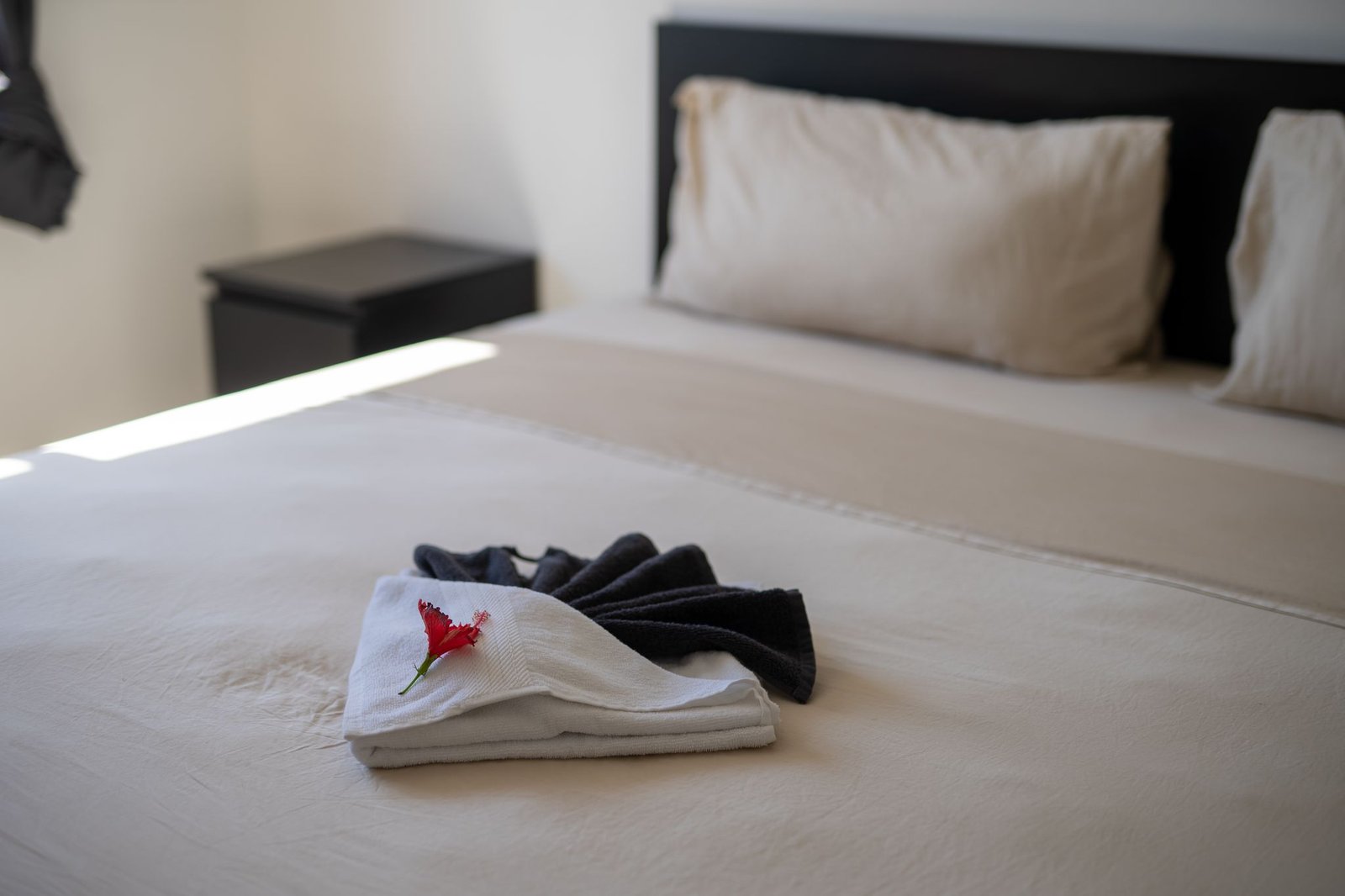 Cama ordenada con toallas y flor roja