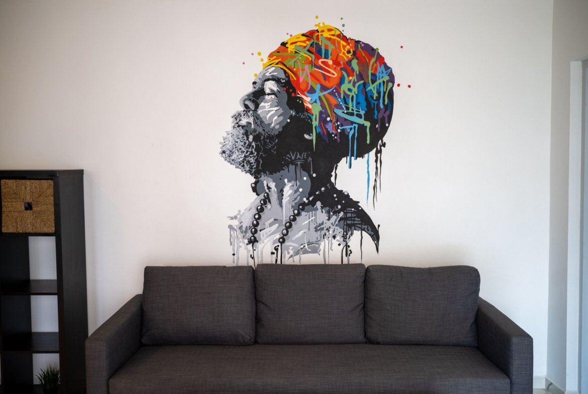 Mural colorido de hombre con turbante sobre sofá gris