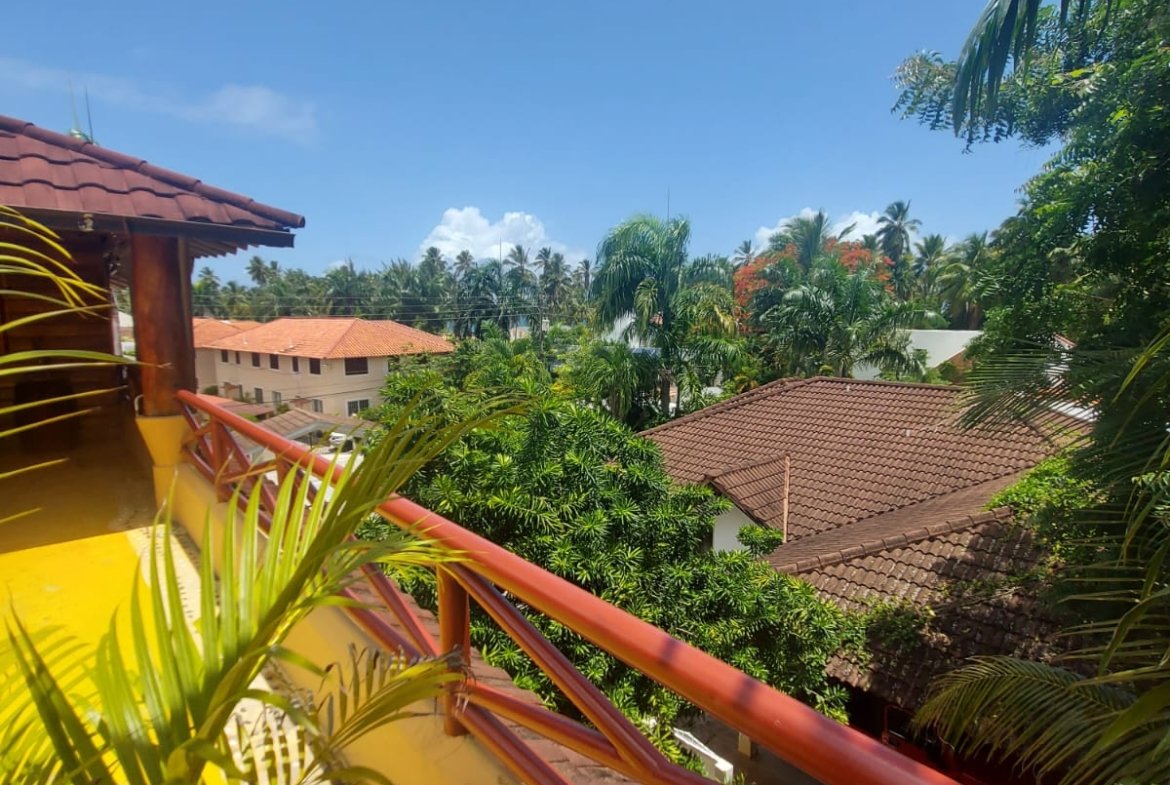 Balcón tropical con vistas a palmeras y tejados