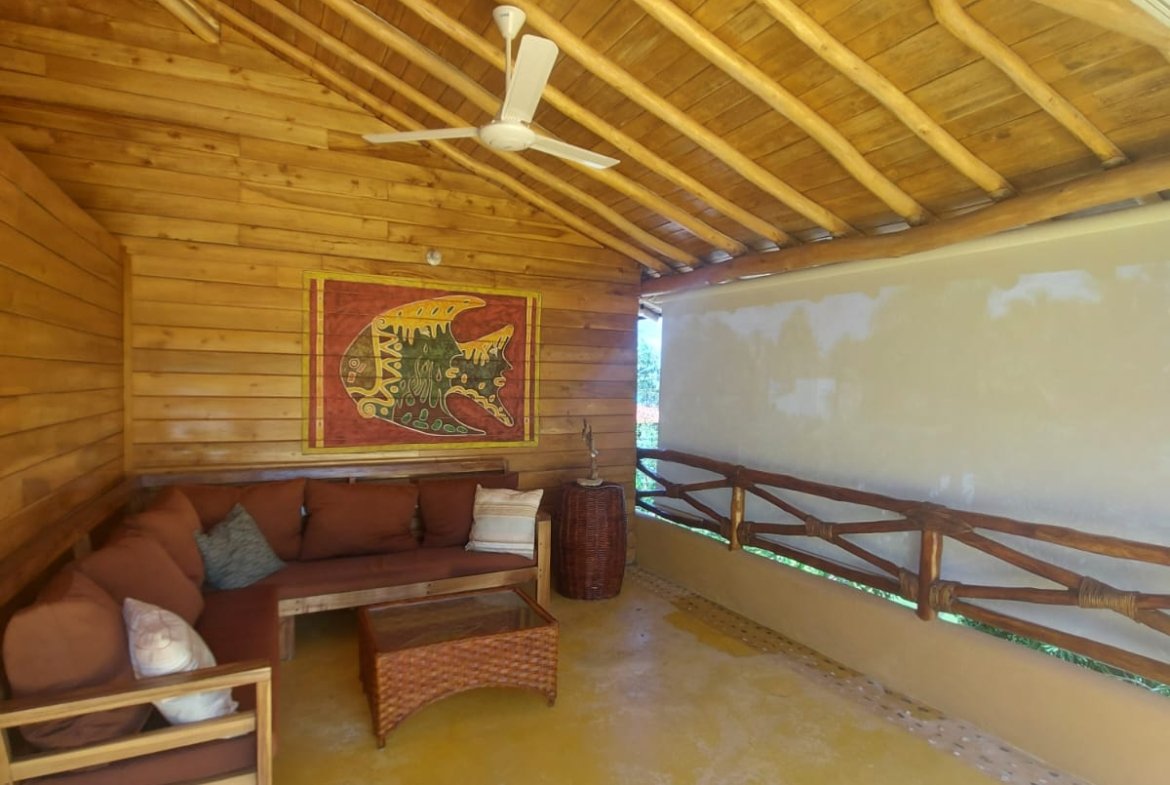 Porche rústico de madera con sofá y ventilador