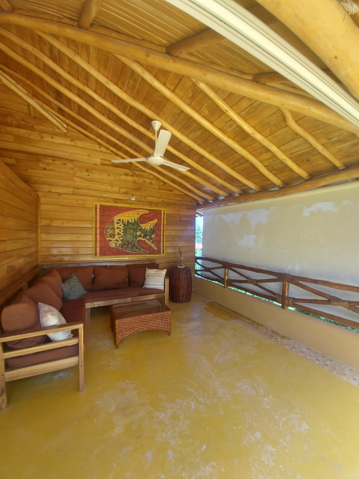 Porche rústico de madera con sofá y ventilador