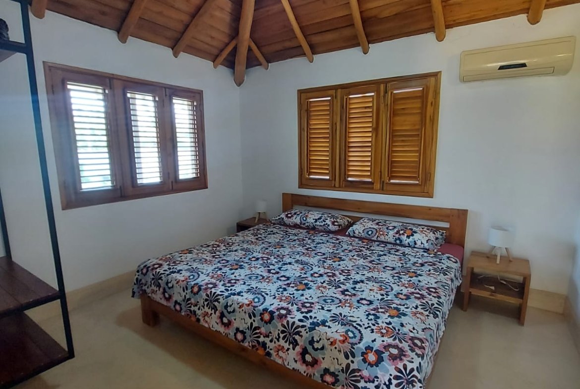 Dormitorio acogedor con techo de madera y ventilador