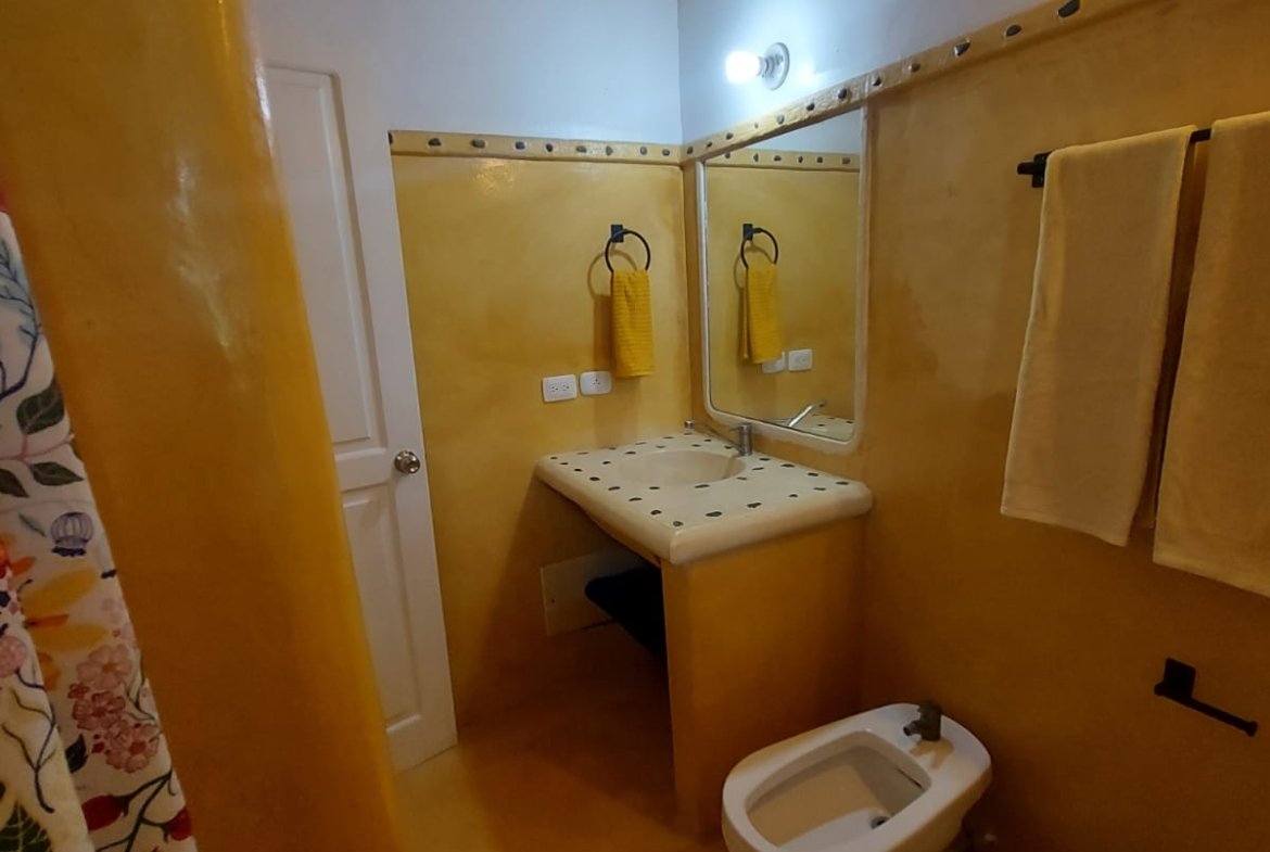Baño amarillo con lavabo, espejo y bidé