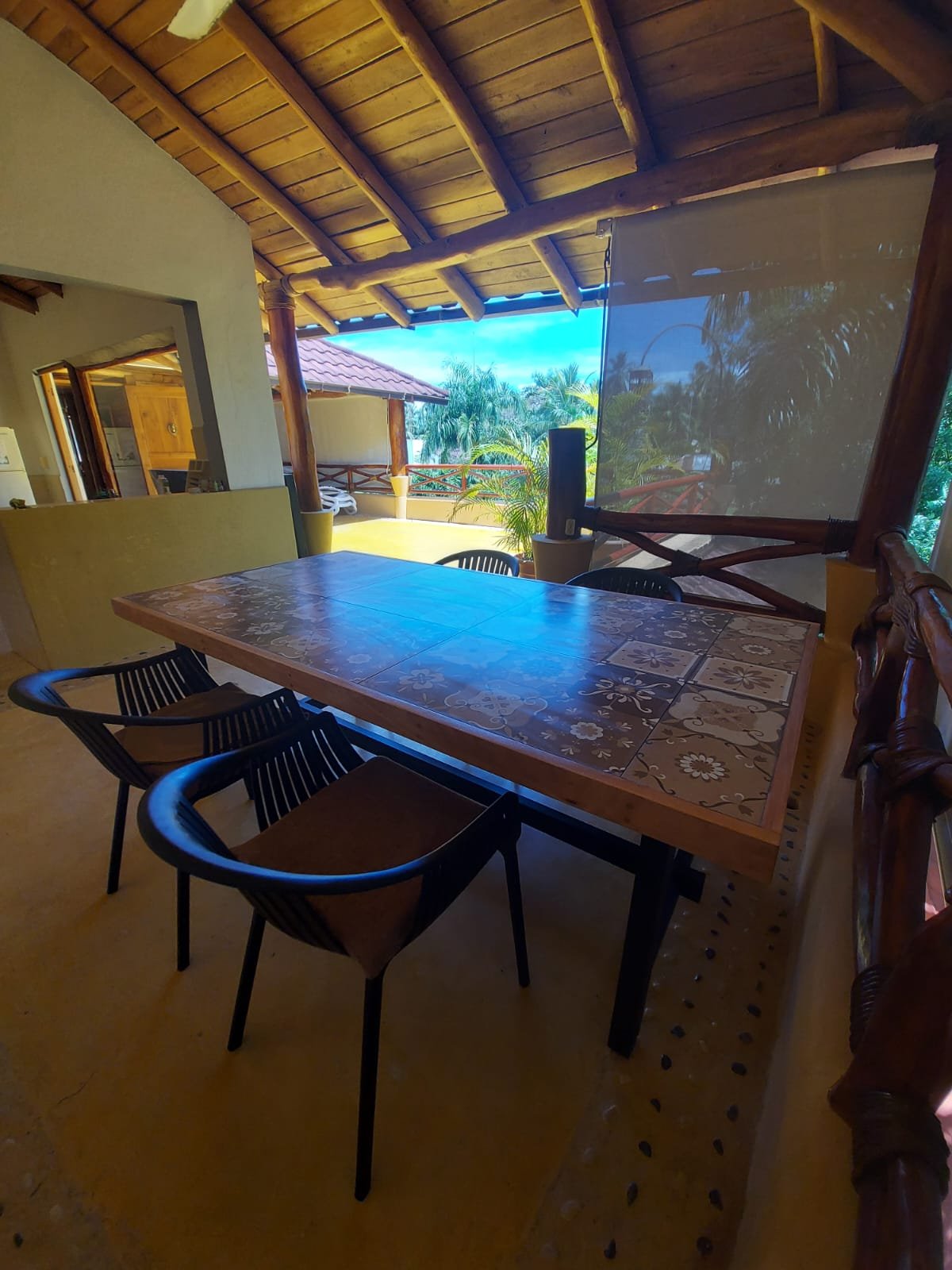 Terraza cubierta con mesa y vistas tropicales