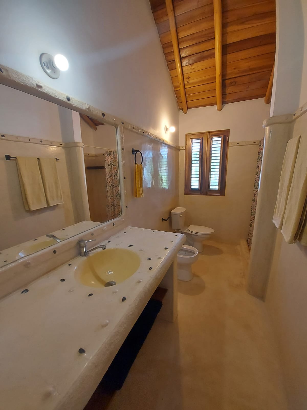Baño rústico con techo de madera y ventana