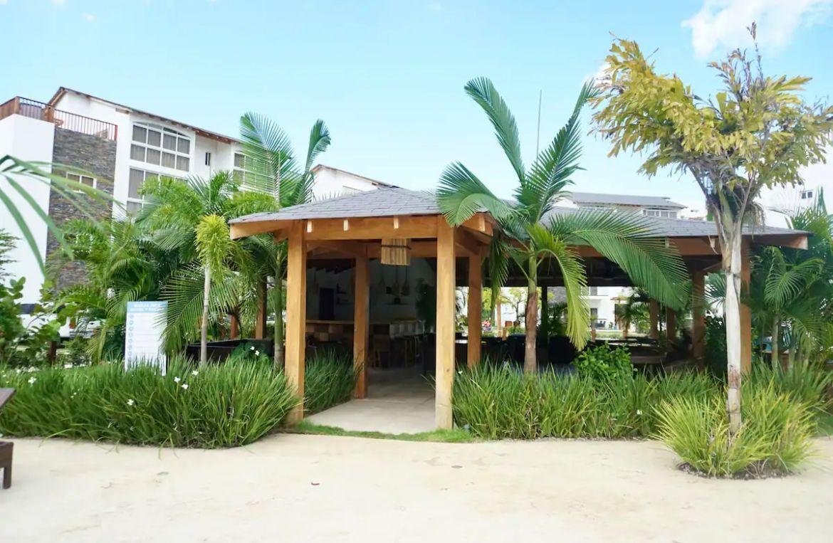 Pérgola de madera rodeada de palmeras y jardín