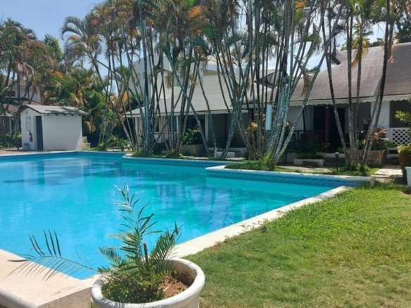 Piscina tropical con palmeras y bungalows blancos