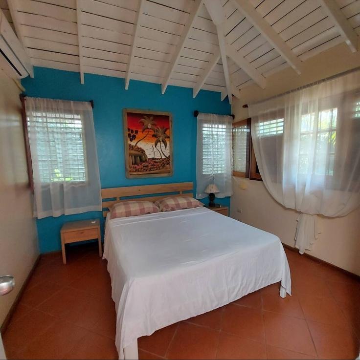 Dormitorio luminoso con cama blanca y paredes azules