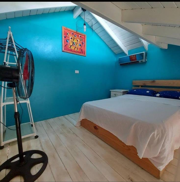 Dormitorio abuhardillado con paredes turquesa y cama doble
