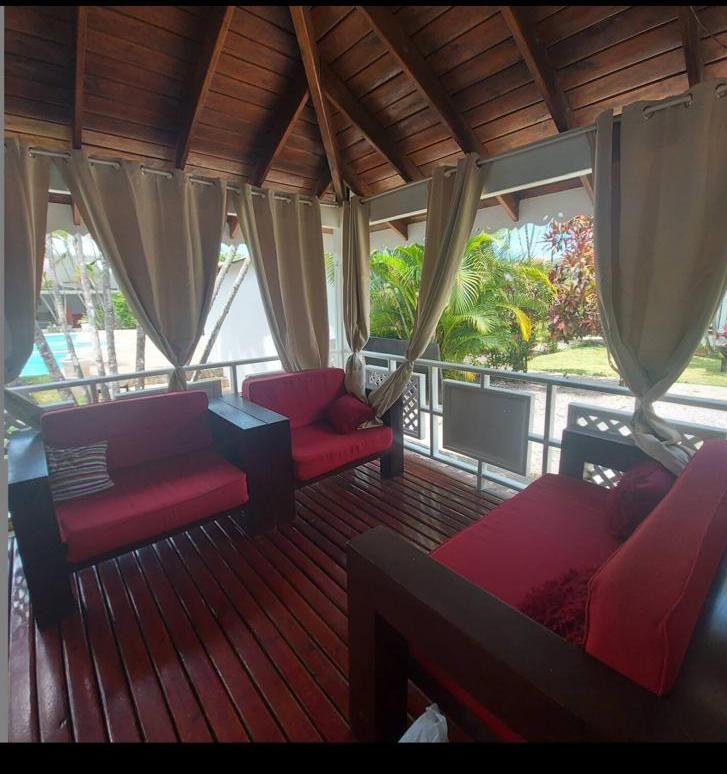 Terraza cubierta con sofás rojos y jardín tropical