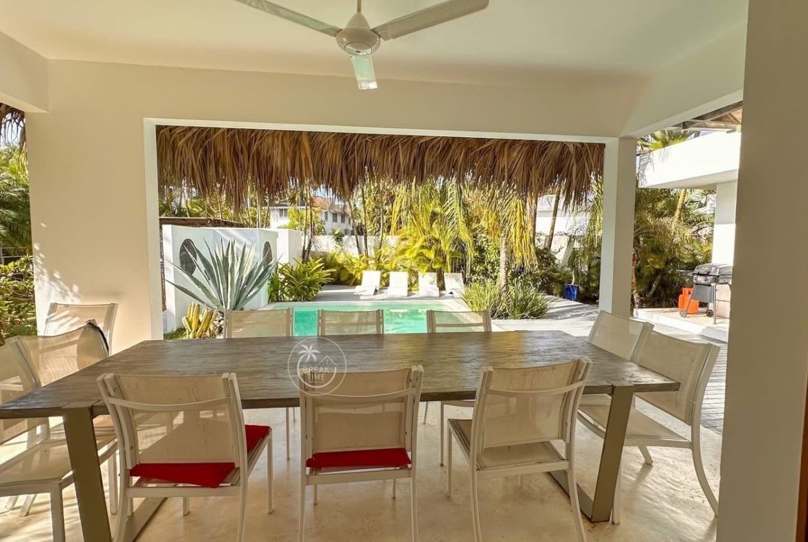 Terraza cubierta con comedor y piscina tropical