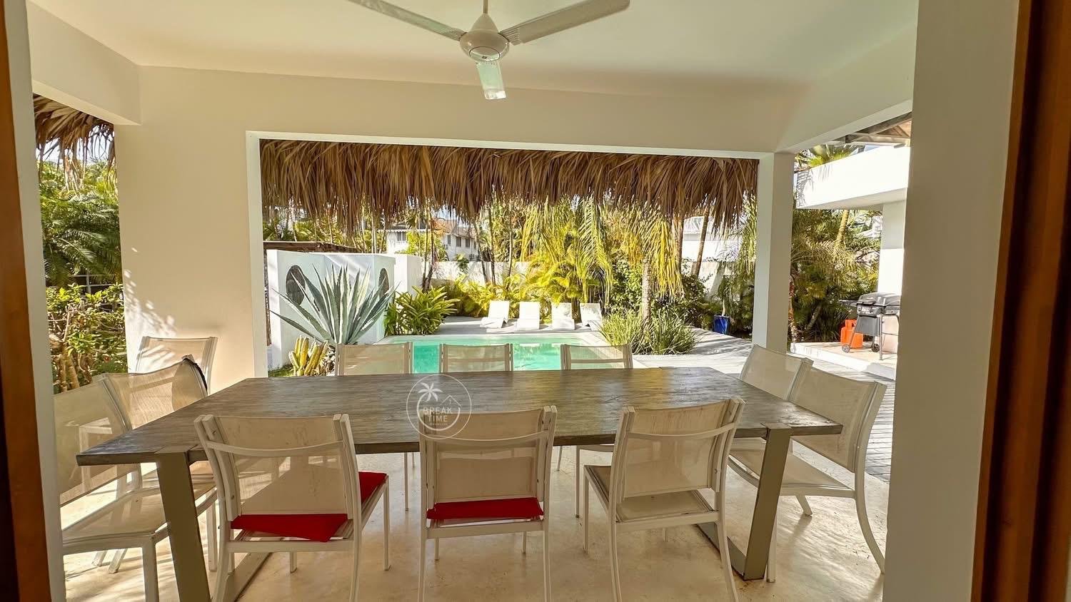 Terraza cubierta con comedor y piscina tropical
