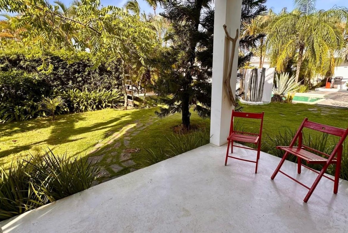 Porche con sillas rojas y jardín tropical